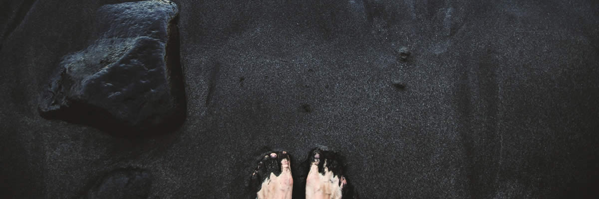 Pé na areia preta molhada